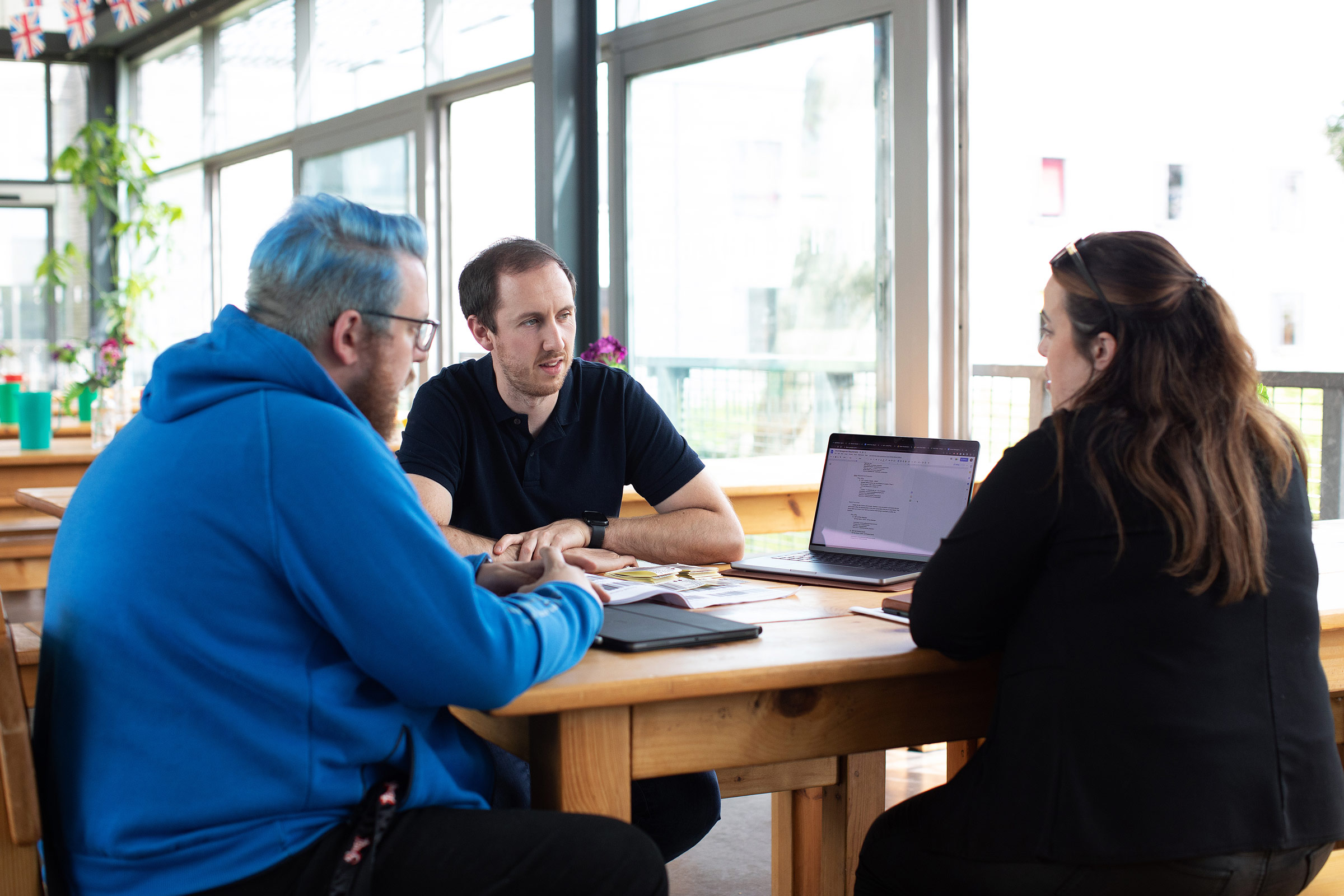 Three people at a laptop, sitting down, two male, one femal