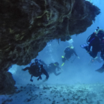 Scuba Divers in Cozumel, Mexico swimming through a coral cave