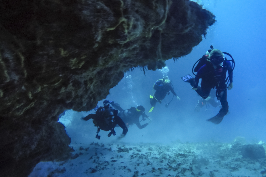 Scuba Divers in Cozumel, Mexico swimming through a coral cave