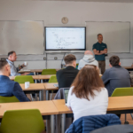 A dozen or so people in a classroom setting having a discussion