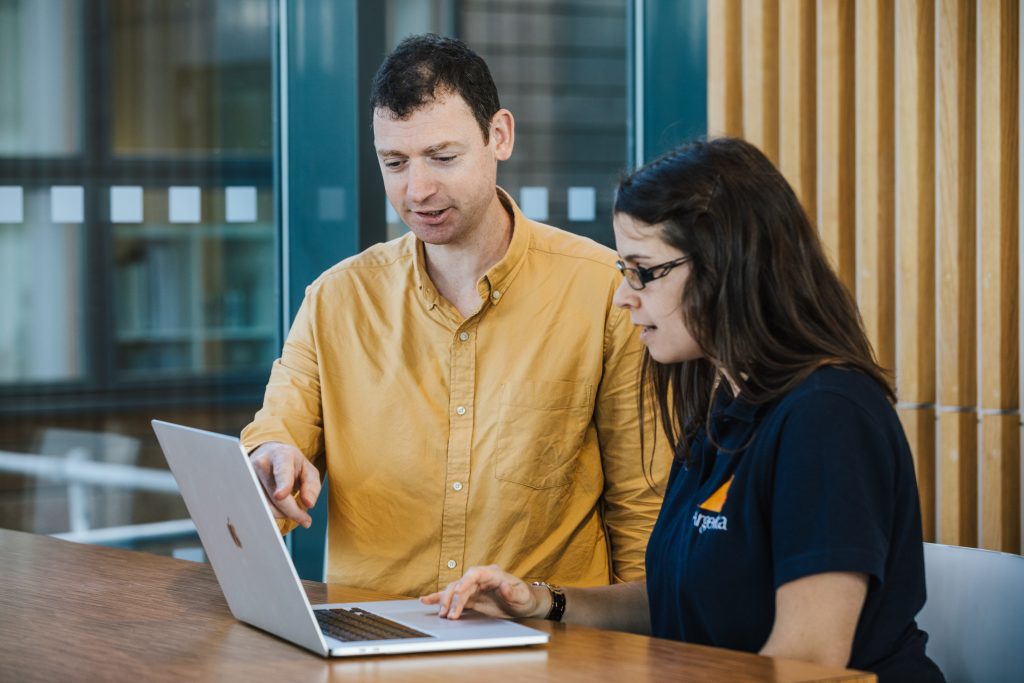 One man and one woman pointing at a laptop
