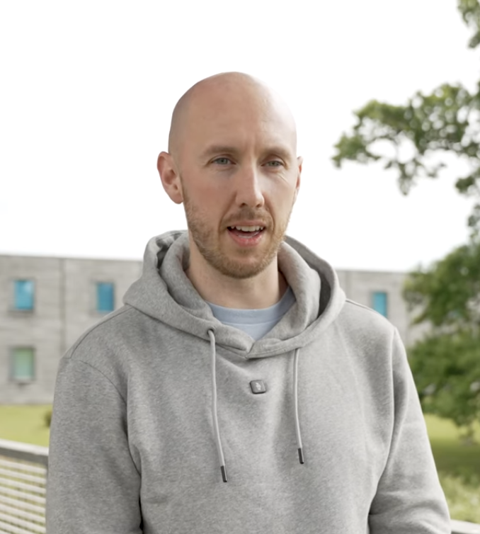 Man in grey hoody talking to camera