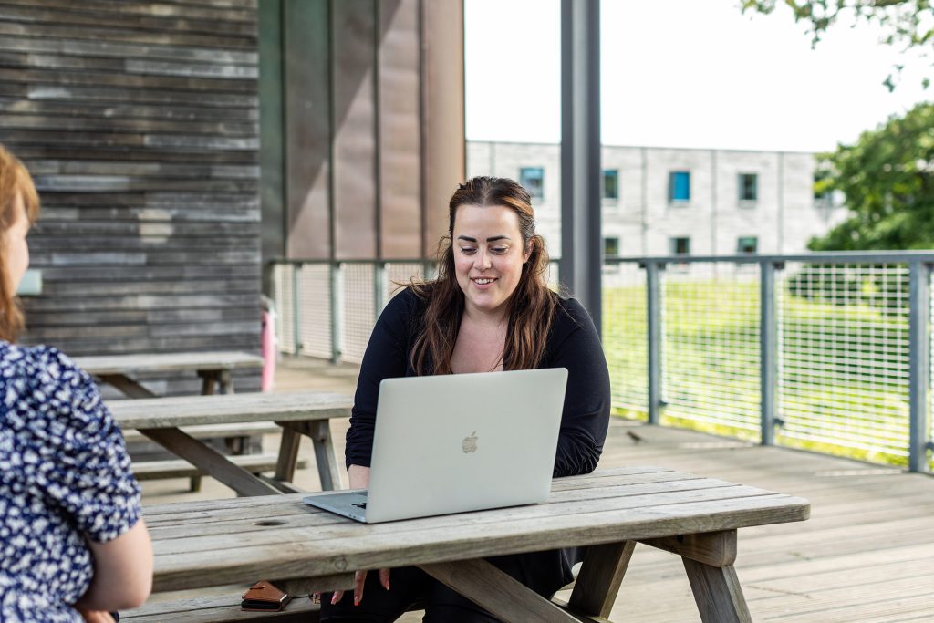On woman working outside looking at her laptop 